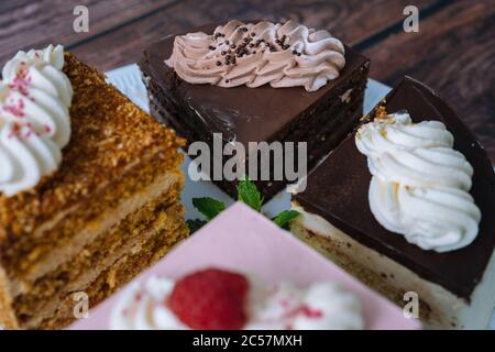 Collection of various cakes on wood background. Assortment of pieces slices with cream. Plate with different types of sweets. Several slices of delicious desserts. confectionery menu concept Stock Photo
