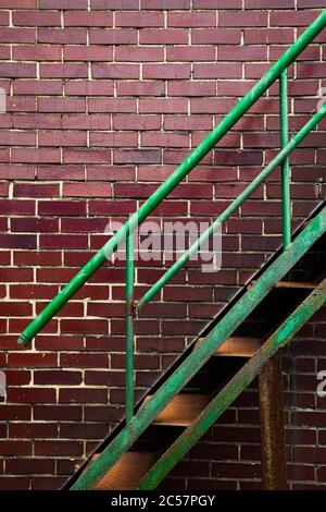 Rusty green iron stairs with brown brick wall background Stock Photo