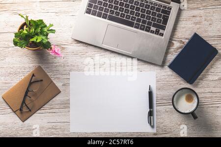 bright wooden office desk with laptop, glasses, notebook and empty scheet of paper Stock Photo