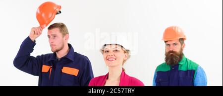 Female manager concept. Team of architects, builders, labourers ready to work, isolated white background. Woman in hard hat with smiling face stand in front of male builders in uniform, defocused. Stock Photo