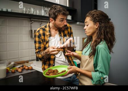 Multiethnic couple is unhappy because cookies they have made are burnt. Stock Photo