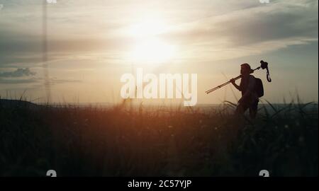 Man silhouette carrying tripod Stock Photo