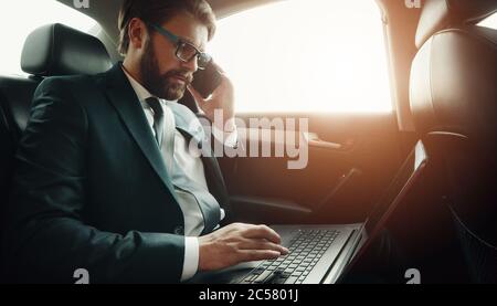Businessman using gadgets in car Stock Photo