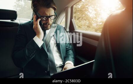 Businessman using electronics in car Stock Photo