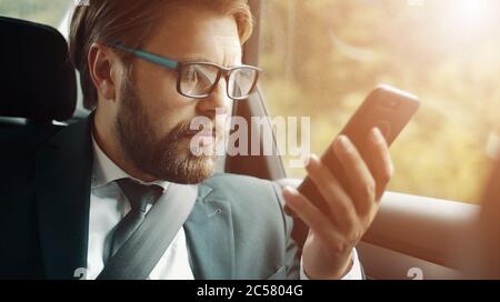Businessman holding smartphone sitting car Stock Photo