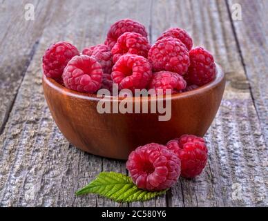Ripe sweet healthy organic raspberries in a bowl on the old rustic table. Close up, side view, high-resolution product image. Stock Photo