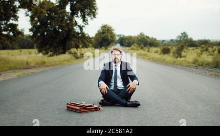 Businessman meditating in middle road Stock Photo