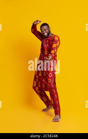 Funny handsome guy in african dress posing over yellow Stock Photo