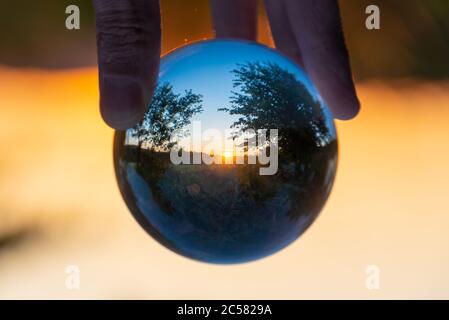 Rural landscape with trees at sunset seen through a crystal ball Stock Photo