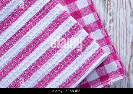 A stack of towels and napkins lying on the table. Clean kitchen towels, hand wipes lying on the table. Order in the kitchen. Colored napkins, towels. Stock Photo