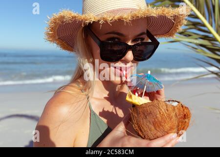 Portrait of woman drinking coconut cocktail on the beach Stock Photo