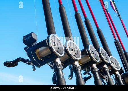 Fishing trolling boat rods in rod holder. Big game fishing. Fishing reels and rods pattern on boat. Sea fishing rods and reels in a row Stock Photo