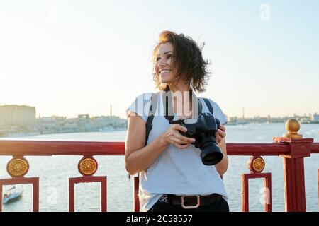 Mature female photographer with professional camera and backpack Stock Photo