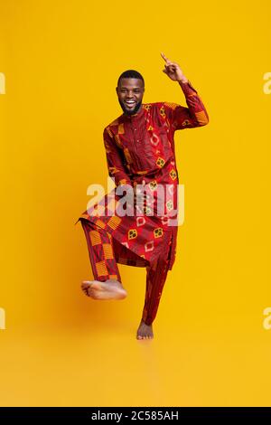 Cheery black guy having fun over yellow background Stock Photo