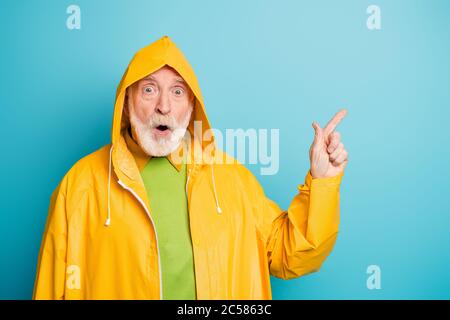 Close-up portrait of his he nice attractive cheerful amazed grey-haired man wearing yellow coat showing ad advert advice solution isolated on bright Stock Photo