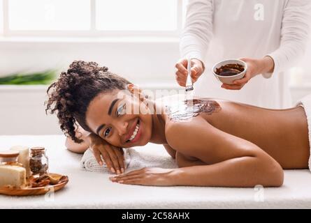 Cheerful black girl enjoying spa procedures at salon Stock Photo