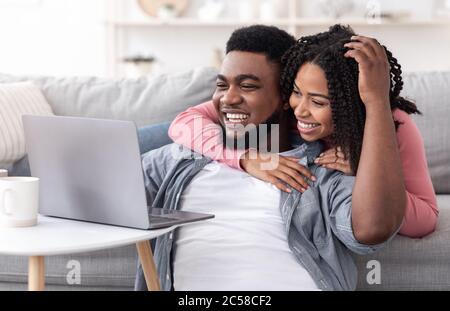 Caring Black Woman Supporting Boyfriend While He Working On Laptop At Home Stock Photo