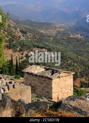 Greece, Phocis, Delphi. Ruins of the Sanctuary of Delphi - the reconstructed treasury in the foreground. UNESCO World Heritage Site. Stock Photo