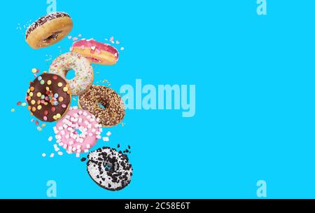 flying glazed round doughnuts. Mix of multicolored sweet donuts with sprinkles on blue background Stock Photo