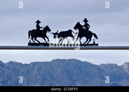 Wrought iron ranch sign at gate in Chihuahuan Desert near Presidio, Texas, USA with Sierra Grande massif across Rio Grande in Mexico in distance Stock Photo