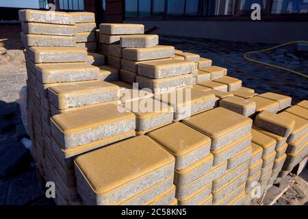 New yellow paving slabs folded in a pile one on top of another on a sunny day, side view close up. Stock Photo