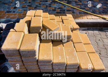 New yellow paving slabs folded in a pile one on top of another on a sunny day, close up view. Stock Photo