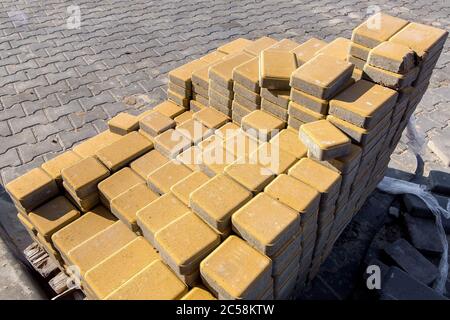 New yellow paving slabs folded in a pile one on top of another on a sunny day, close up. Stock Photo