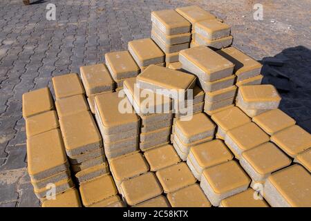 New yellow paving slabs piled in a pile one on top of another on a sunny day, close up. Stock Photo