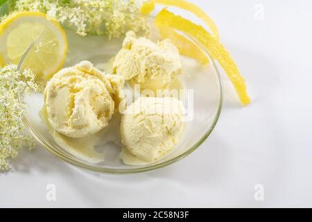 Homemade ice cream from elderberry flowers and lemon in a glass bowl on a light gray table, copy space, selected focus, narrow depth of field Stock Photo