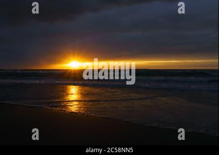 Sunset over the sea. Reflection of sunlight in the sea waves. Red sky in the rays of the sunset. Stock Photo