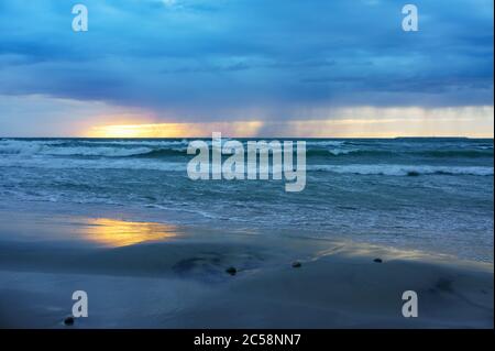 Sunset over the sea. Reflection of sunlight in the sea waves. Red sky in the rays of the sunset. Stock Photo