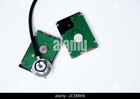 A hard disk with a stethoscope isolated on white background. Recovery and Data Safety Stock Photo