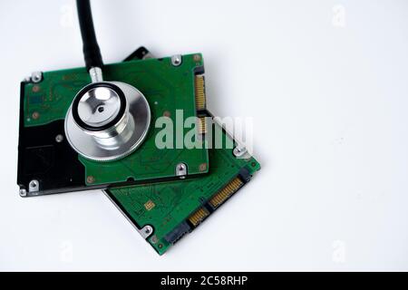 A hard disk with a stethoscope isolated on white background. Recovery and Data Safety Stock Photo