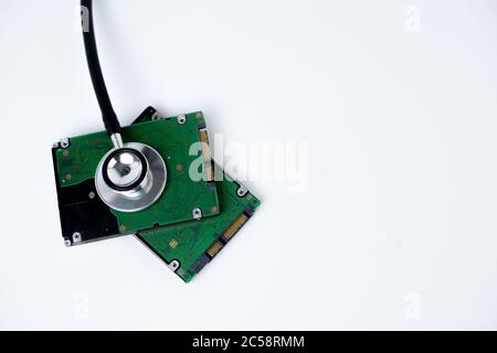 A hard disk with a stethoscope isolated on white background. Recovery and Data Safety Stock Photo
