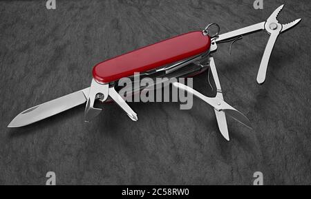 old Swiss knife on a stone background. Top view Stock Photo