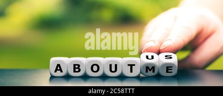 Hand turns dice and changes the expression "about me" to "about us". Stock Photo