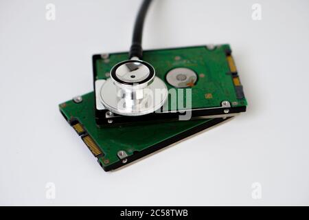 A hard disk with a stethoscope isolated on white background. Recovery and Data Safety Stock Photo