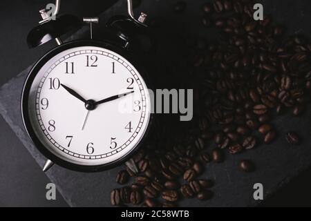 vintage alarm clock and coffee beans on slate stone plate. Selective Focus. Copy Space concept. Celebrate International Coffee Day On October Stock Photo
