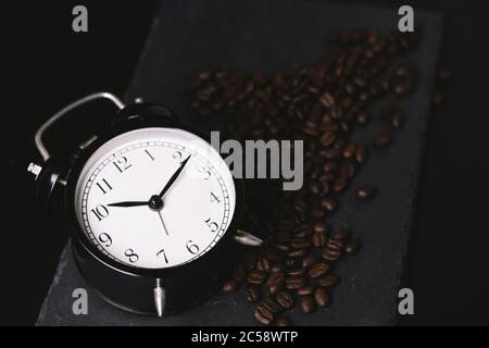 vintage alarm clock and coffee beans on slate stone plate. Selective Focus. Copy Space concept. Celebrate International Coffee Day On October Stock Photo
