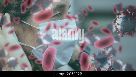 Covid-19 cells against woman wearing face mask Stock Photo
