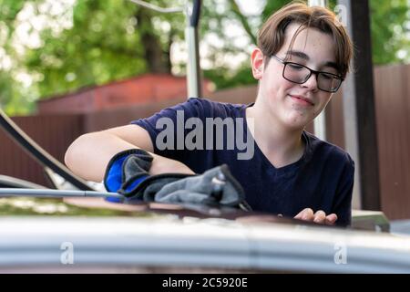 young guy washes a car with a rag Stock Photo