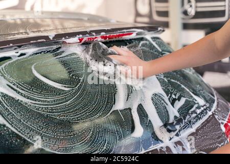 man washes a car with a sponge with foam Stock Photo