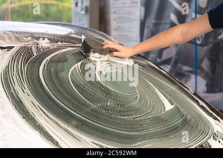 young man washes his car with a sponge Stock Photo