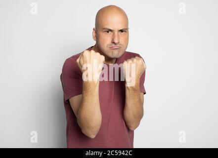 Angry middle aged man shows his fists isolated on grey background Stock Photo