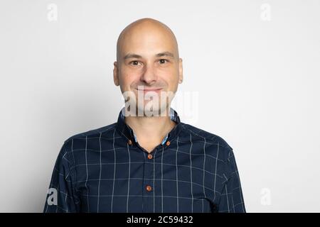 40 years bald man in shirt is smiling over grey studio wall Stock Photo