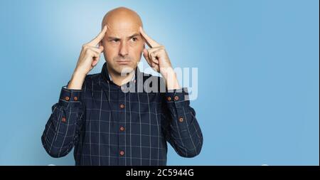 Serious middle aged bald man thinking. Isolated over blue studio background Stock Photo