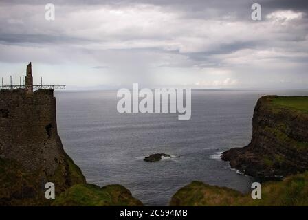 The Dunluce Castle sorrounded by sea, rocks and cloudy days with rain on its way. Stock Photo