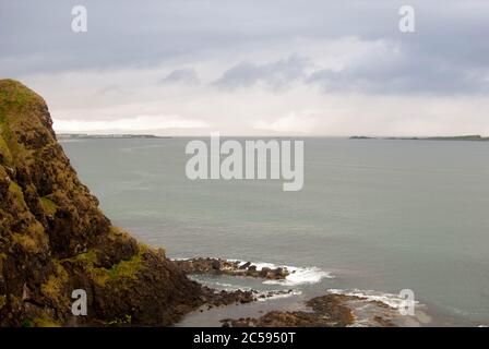 The Dunluce Castle sorrounded by sea, rocks and cloudy days with rain on its way. Stock Photo