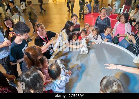SHENZHEN, CHINA - CIRCA APRIL, 2019: people play with Sony's Aibo robot dog at Sony Expo 2019 at UpperHills Mall in Shenzhen, China. Stock Photo