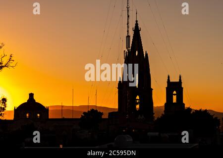 Colorful sunset over the bell towers of the Parroquia de San Miguel Arcangel and the lesser San Rafael Church in the historic city center in San Miguel de Allende, Mexico. Stock Photo